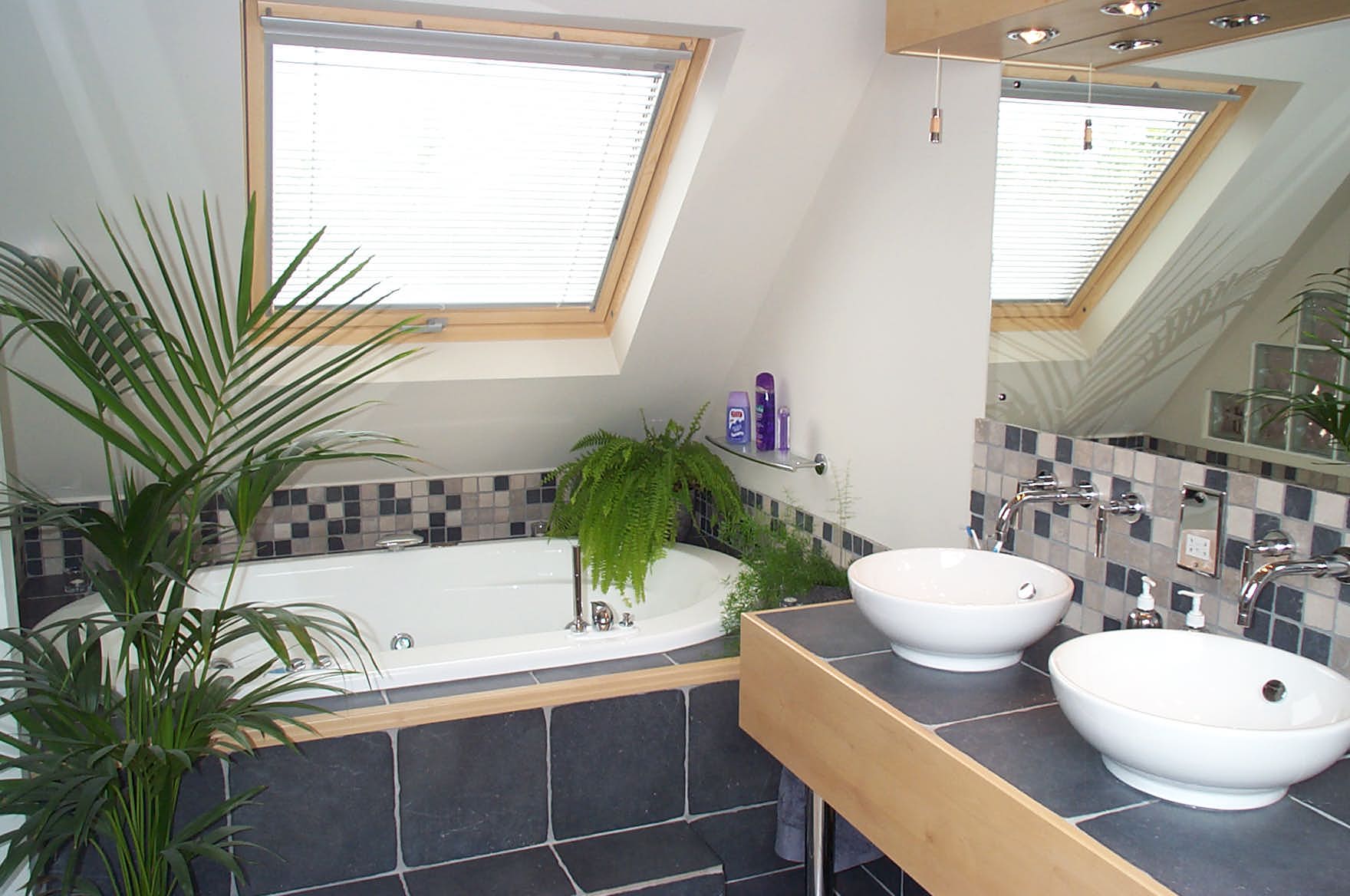 A bathroom with two sinks and a bathtub under a skylight
