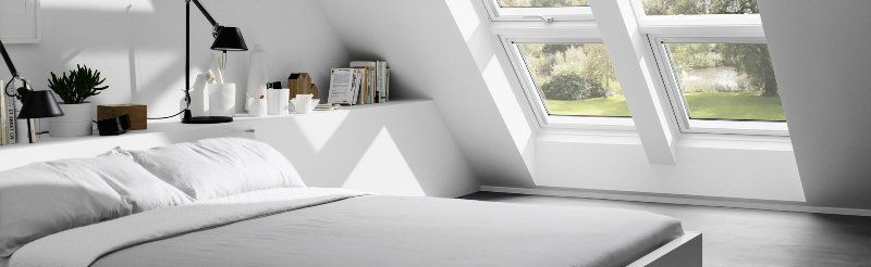 A bedroom with a bed and a lot of windows.