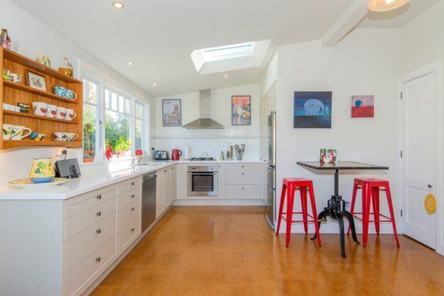 A kitchen with white cabinets and red stools and a table