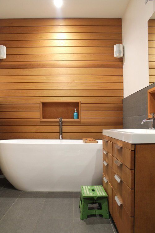 Natural timber walls and cabinets contrast with the white tub and vanity top in this bathroom Natural wood contrasting with white bath