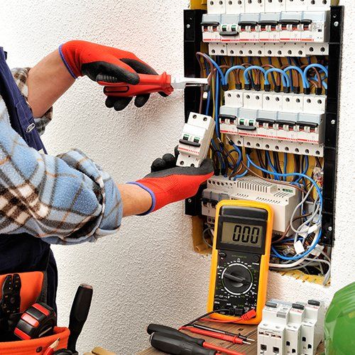 Electric Water Heaters — Man Fixing and Testing Wires in Hockessin, DE