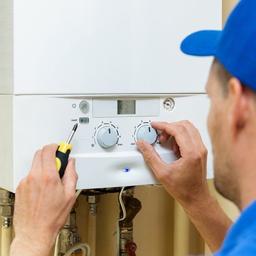 Tankless Water Heaters — Man Fixing Water Heater in Hockessin, DE