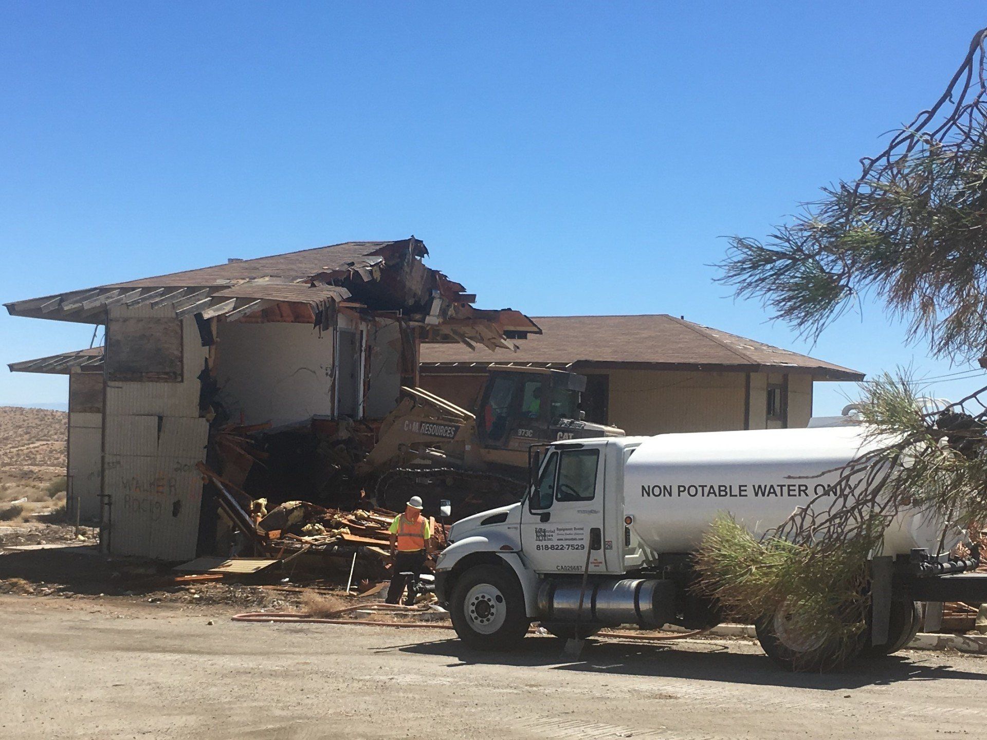 A white truck that says homer williams is parked in front of a demolished house