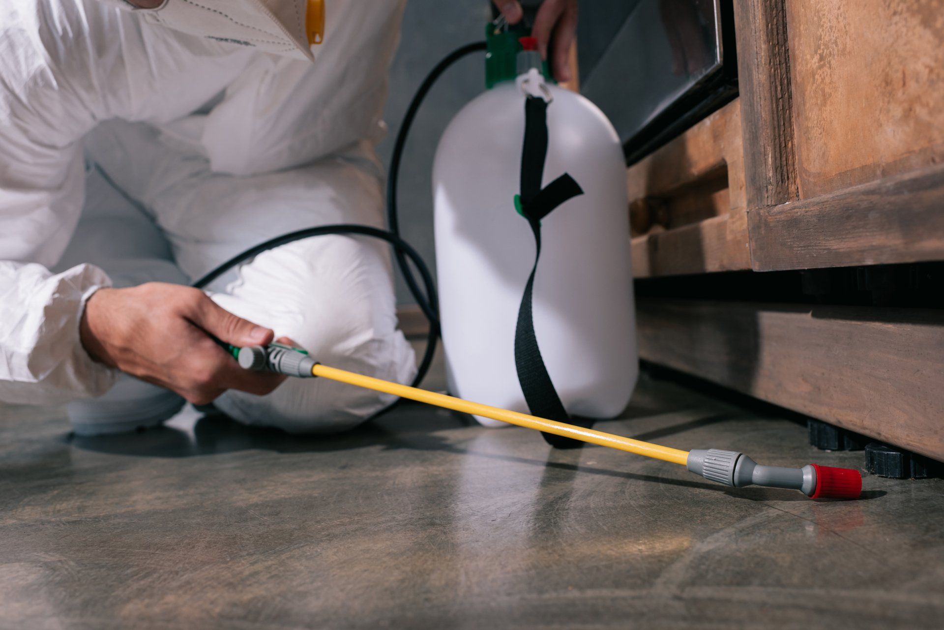 Pest Control Worker Spraying Pesticides On Floor In Kitchen - Pest Control in Mudgee NSW
