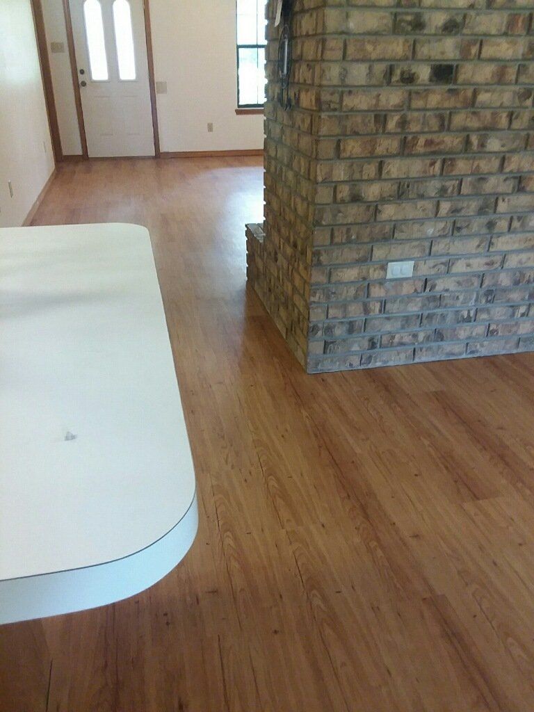 Empty room with wood floor, brick pillar, and white couch edge near the doorway.