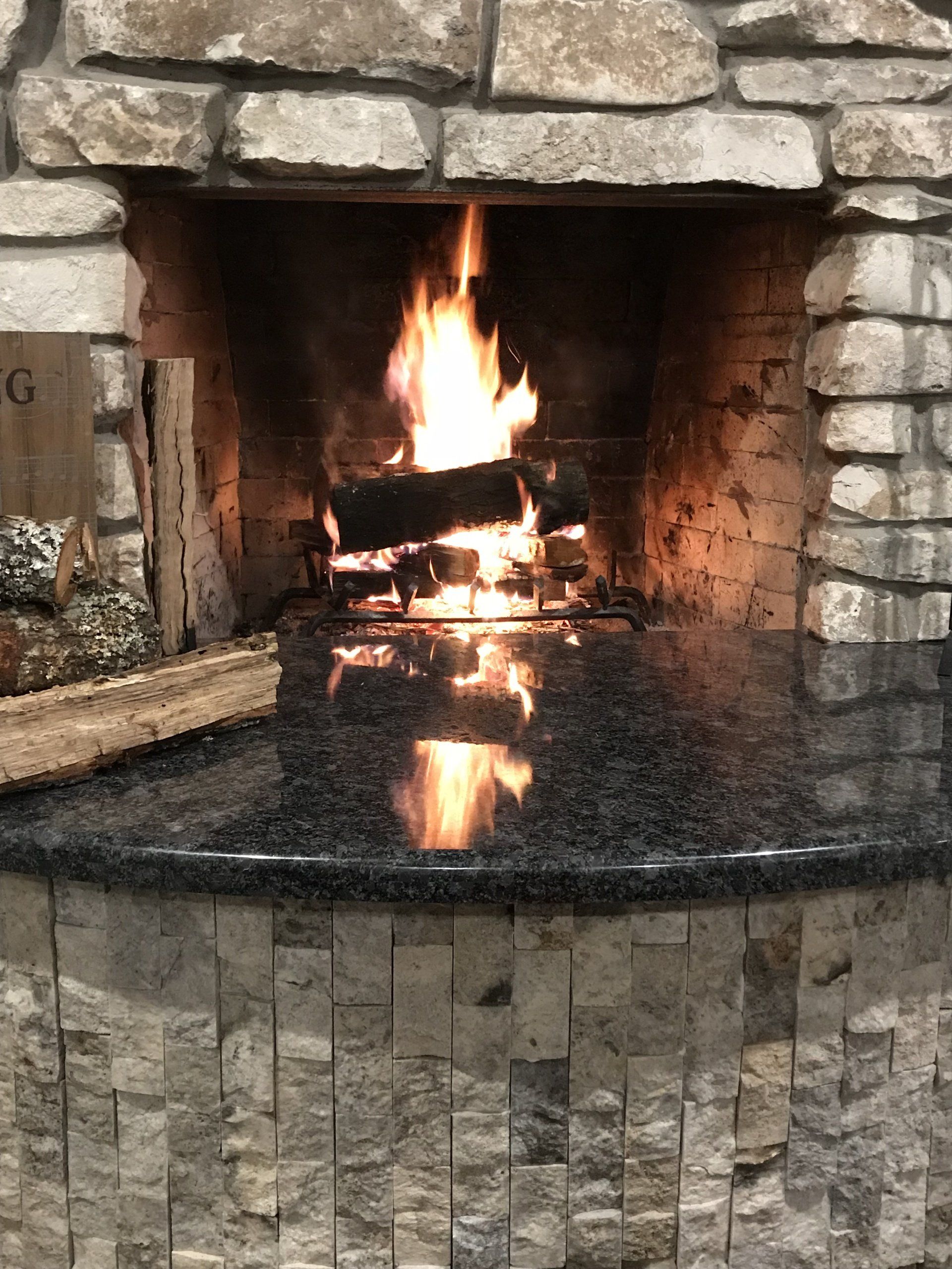 Stone fireplace with a burning fire and a glossy black hearth reflecting the flames