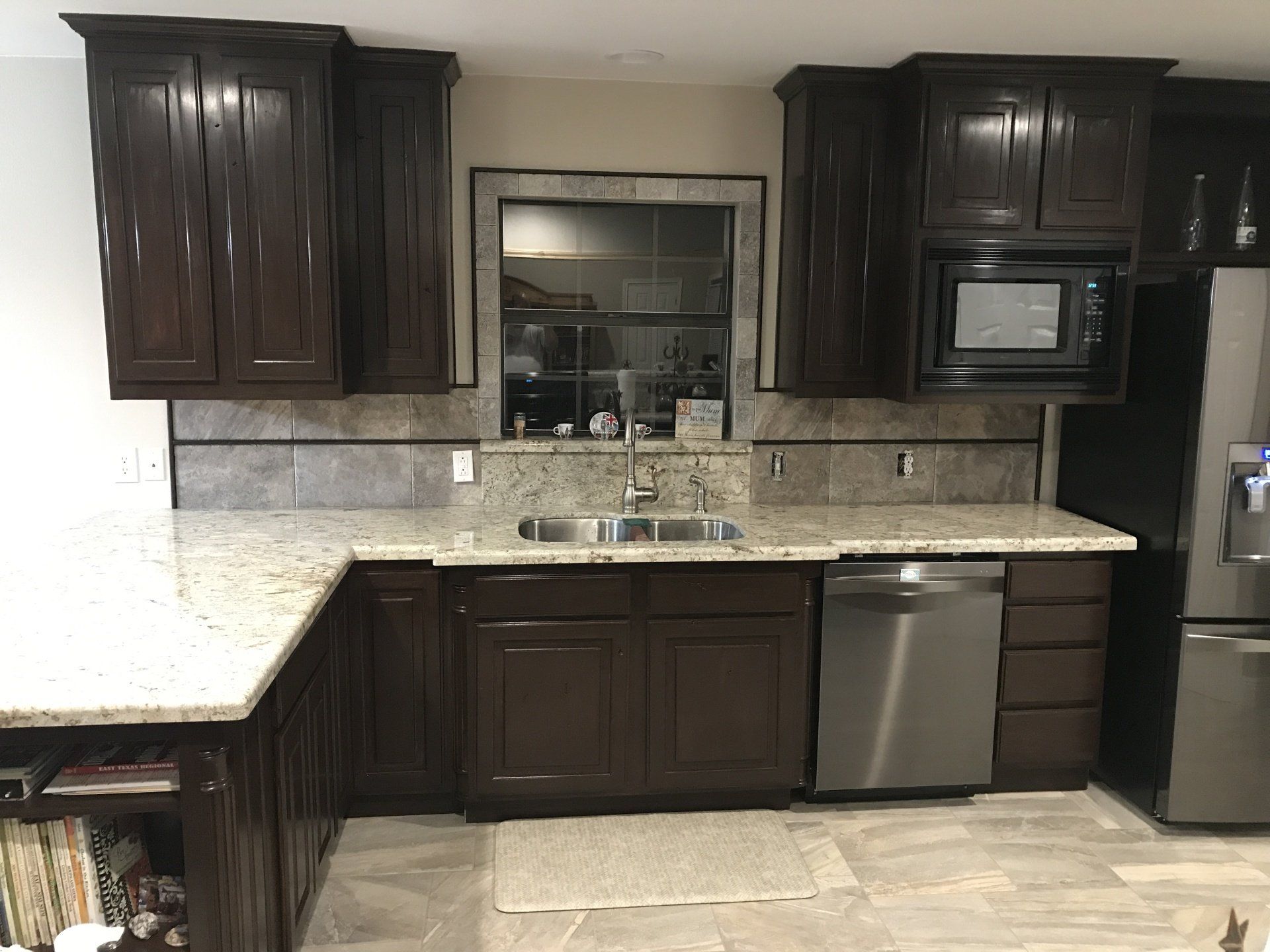 Dark wood kitchen cabinets with granite counters, tiled backsplash, stainless dishwasher, and built-in microwave.