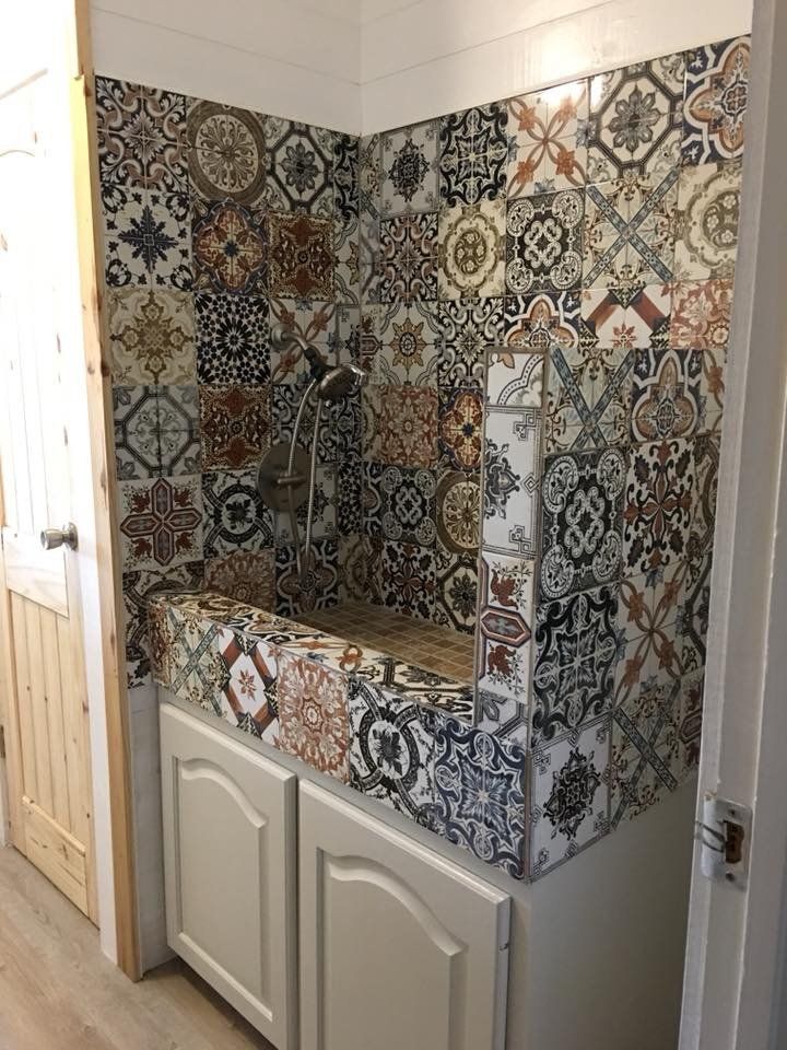 Patterned tile backsplash over a small vanity and sink in a narrow bathroom alcove