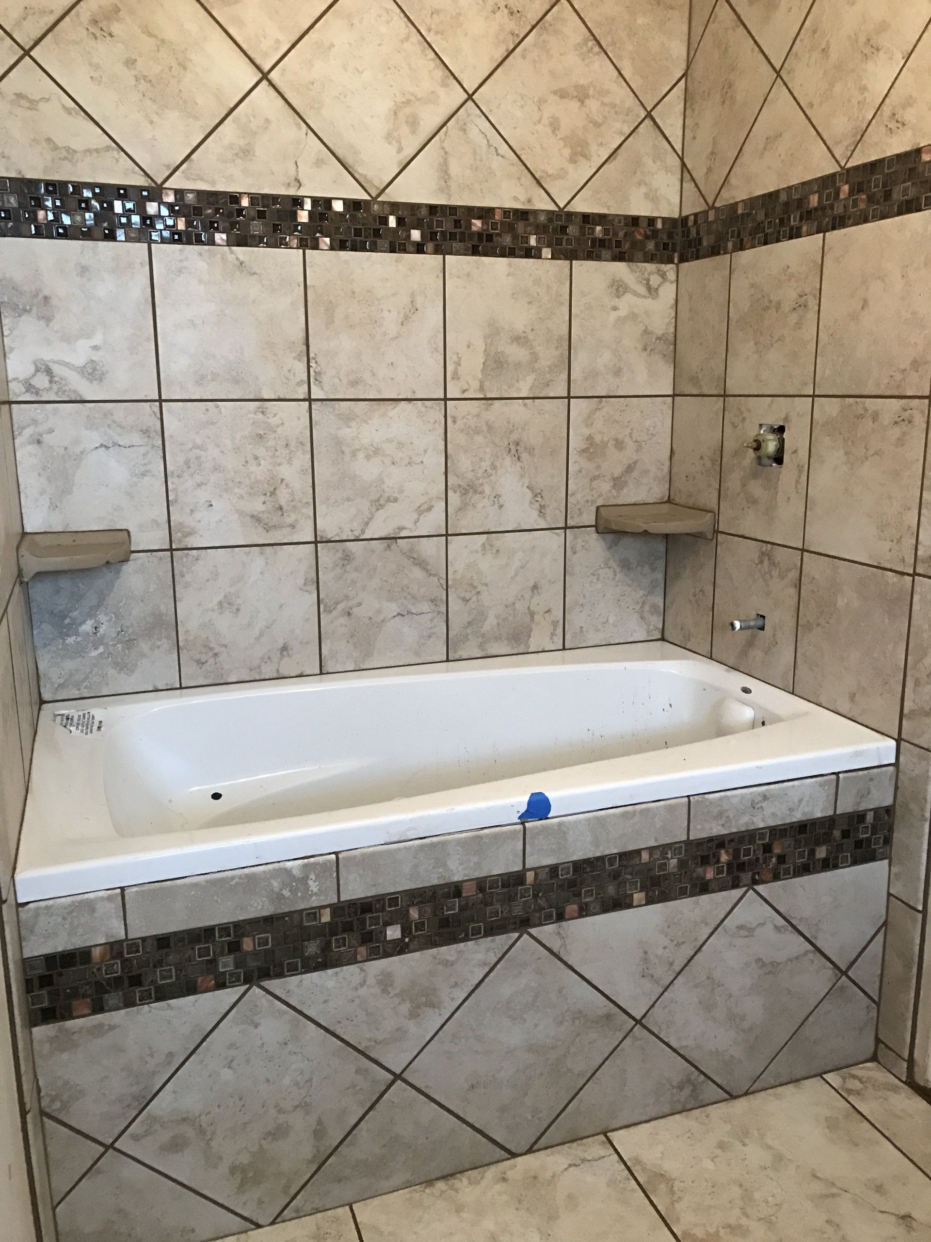 Tiled bathroom with a white bathtub and beige diamond-patterned wall trim
