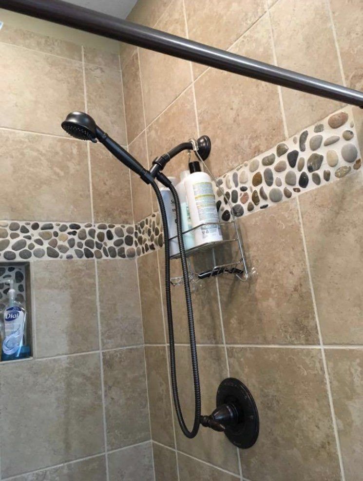 Tiled shower with black handheld showerhead, grab bar, and built-in shampoo bottle holder