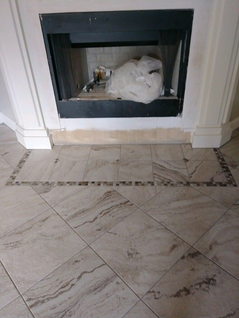 Fireplace with a white bag inside, framed by black trim on a marble-tile floor.
