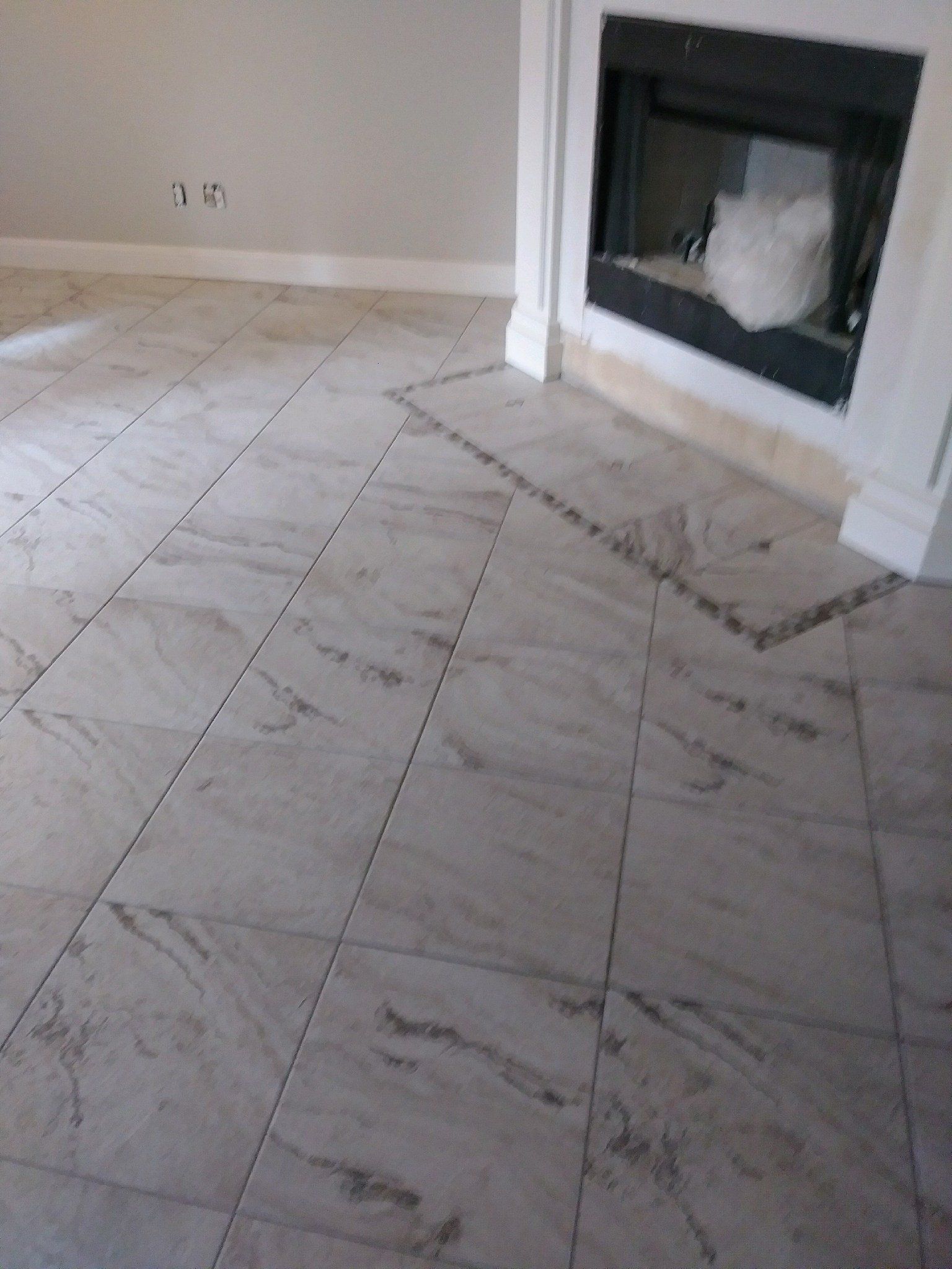 Tiled living room floor leading to a fireplace with white trim and beige walls