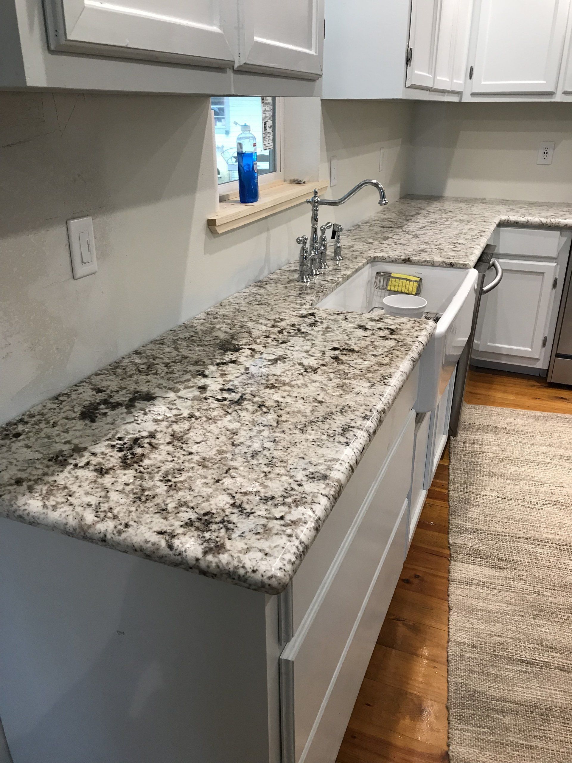 Modern kitchen with speckled granite countertops, gray cabinets, sink, and hardwood floor
