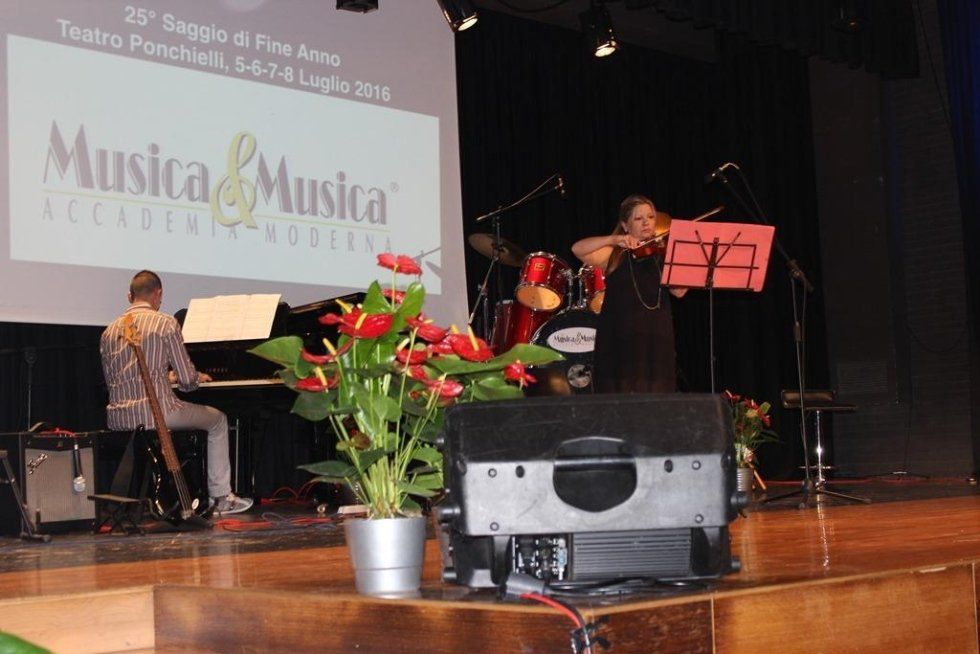 Bouquet di fiori in primo piano con musicista intento a suonare il pianoforte