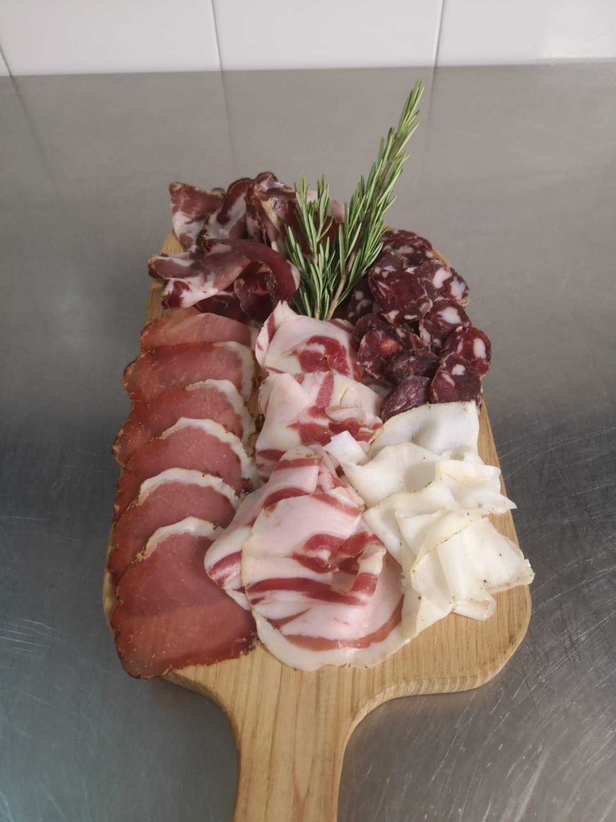 chopping board with mixed cold cuts and rosemary