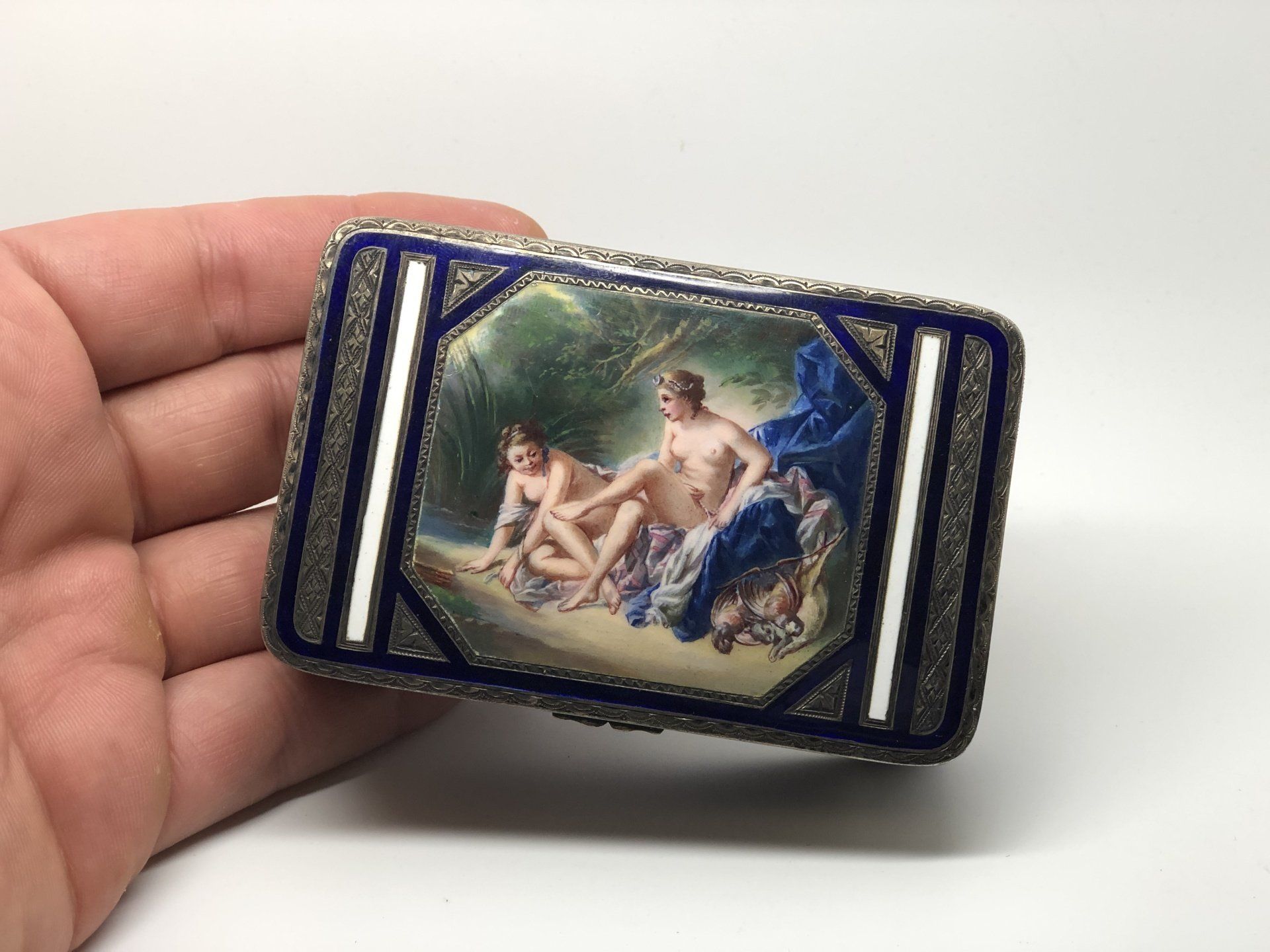 Hand holding a rectangular enameled jewelry box with a mythological scene.