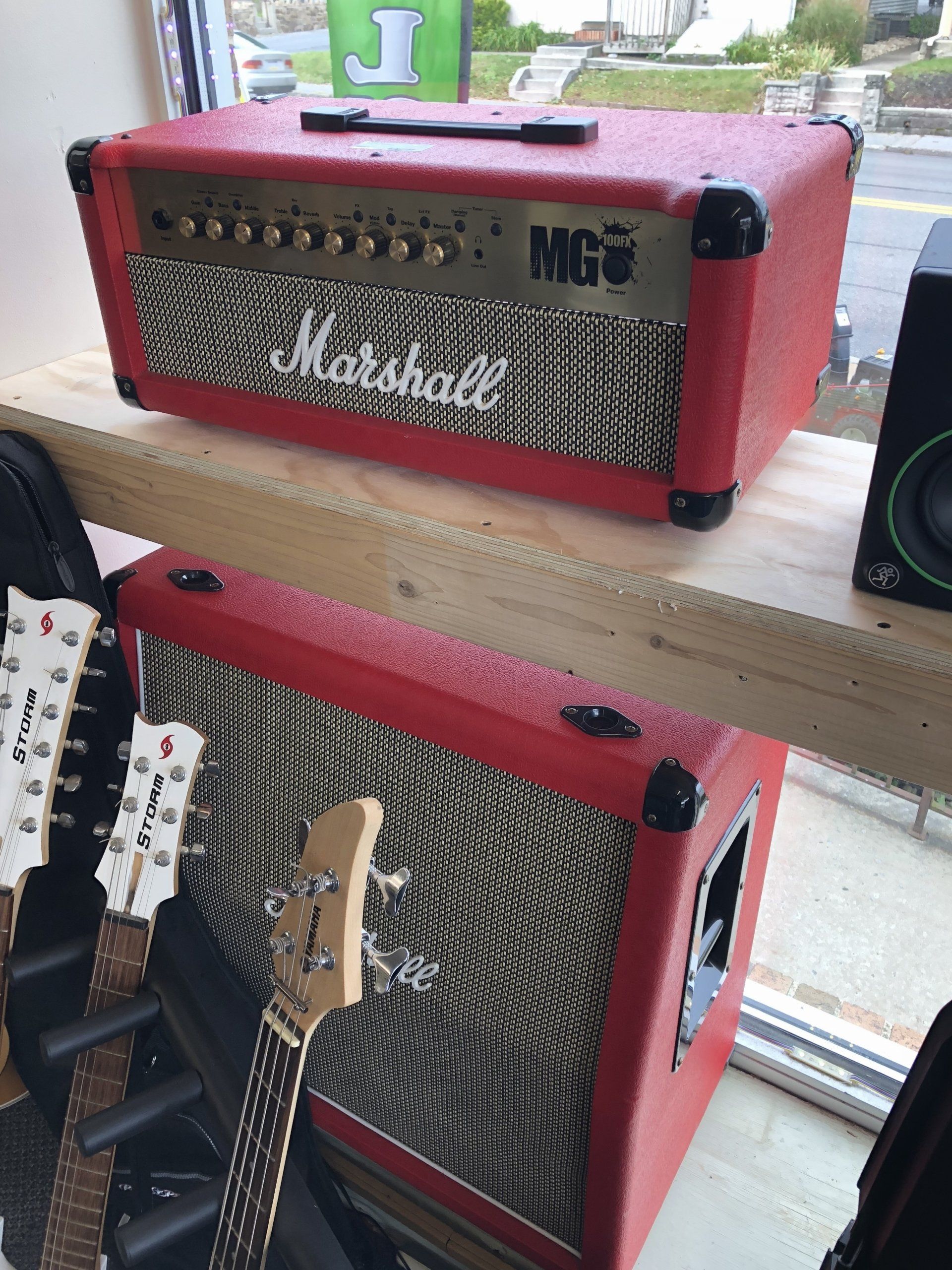 Red Marshall guitar amplifier combo, red covering, black corners, on display with a matching cabinet.