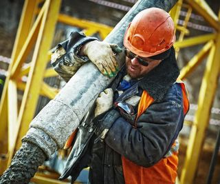 worker carrying a pipe