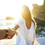woman holding hands with man at the beach
