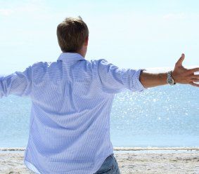man standing at beach with open arms