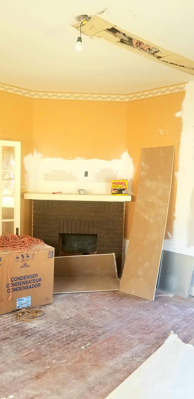 A living room with a fireplace and boxes on the floor.