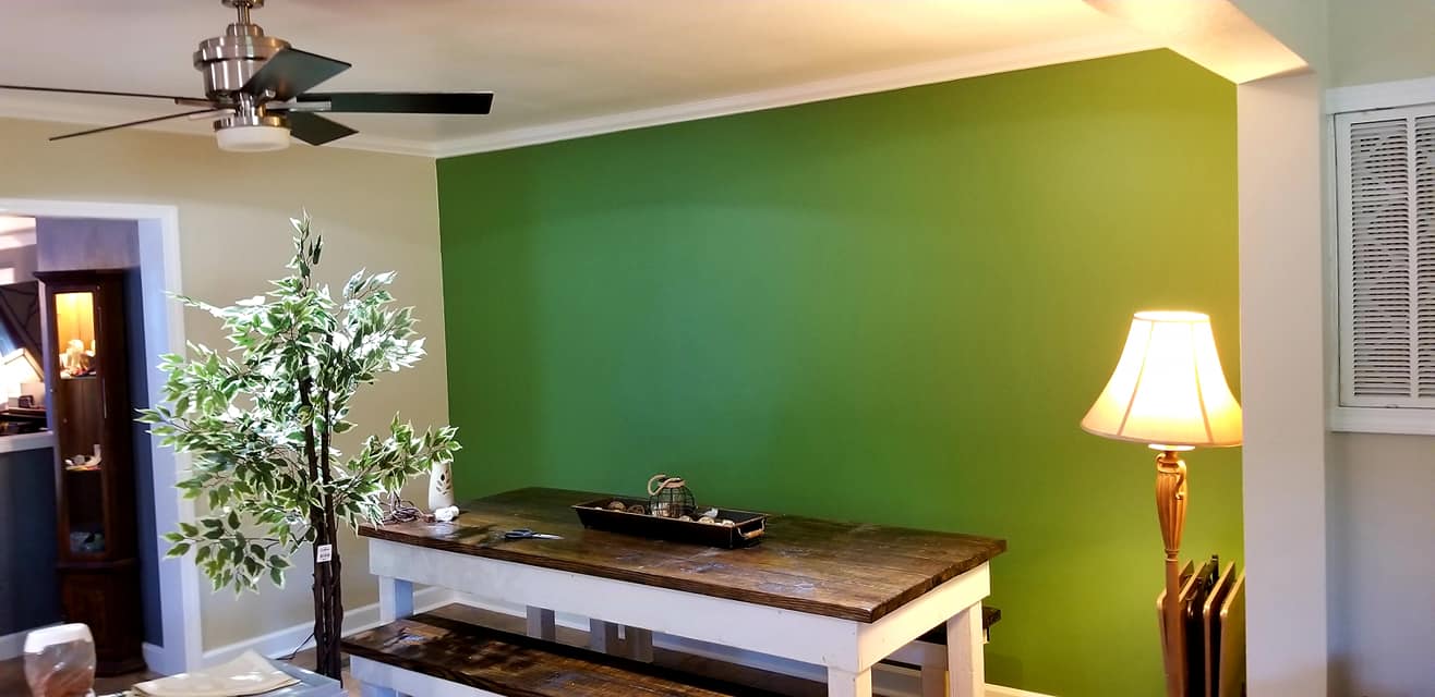 A living room with green walls and a ceiling fan
