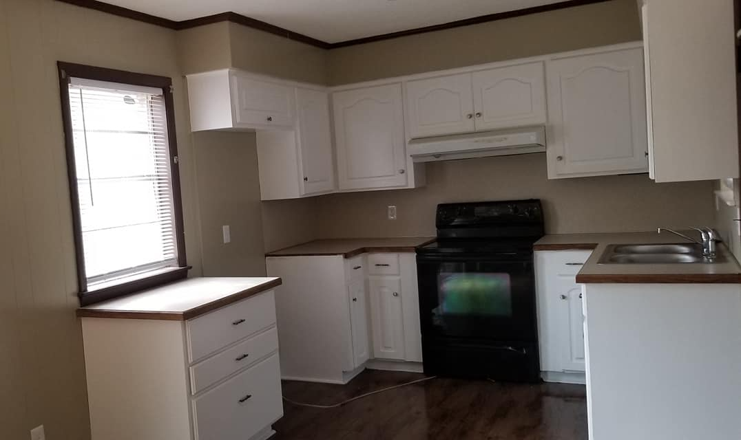 An empty kitchen with white cabinets and a black stove