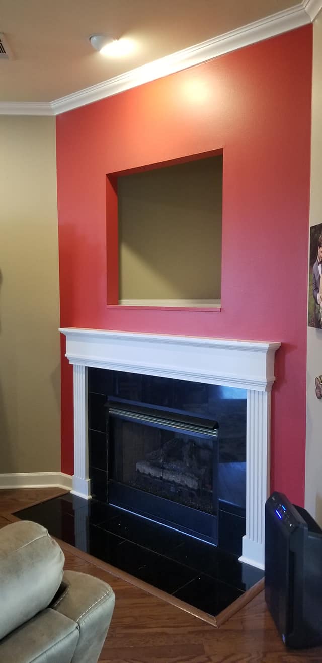 A living room with a fireplace and a red wall.