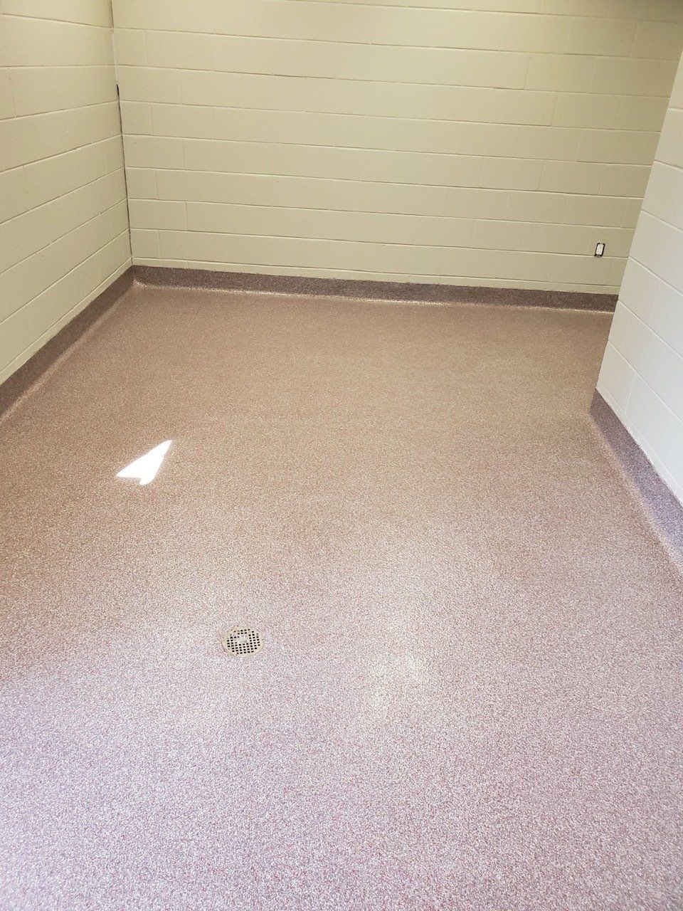 A room with a pink floor and white brick walls.
