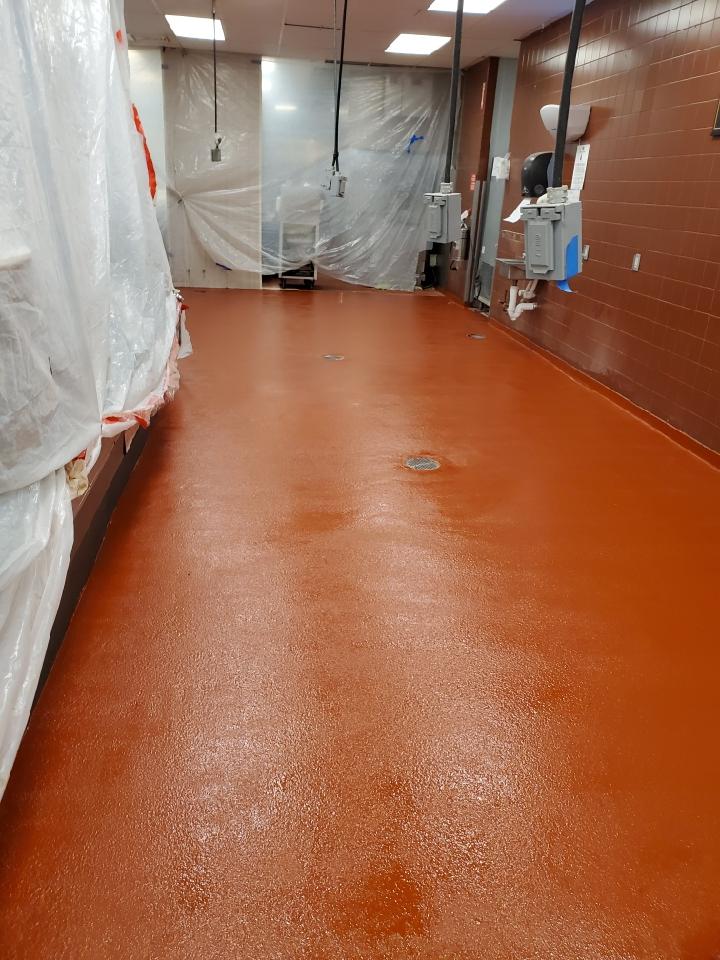 A large room with a red floor and a white tarp on the wall.