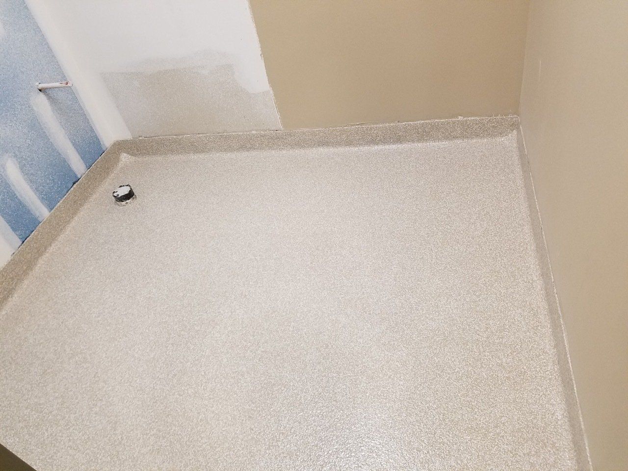 A room with a white floor and a drain on the floor.