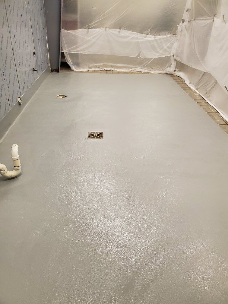 A bathroom with a gray floor and a white pipe.