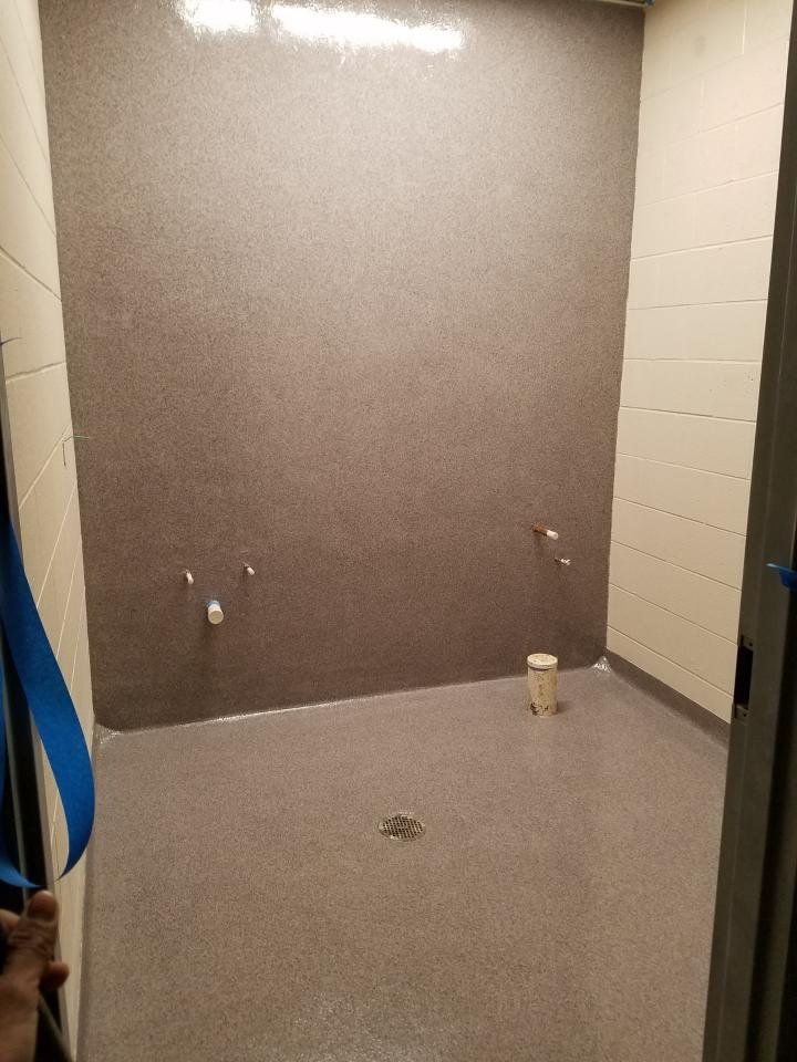 A bathroom with a bucket on the floor and a bucket on the wall.