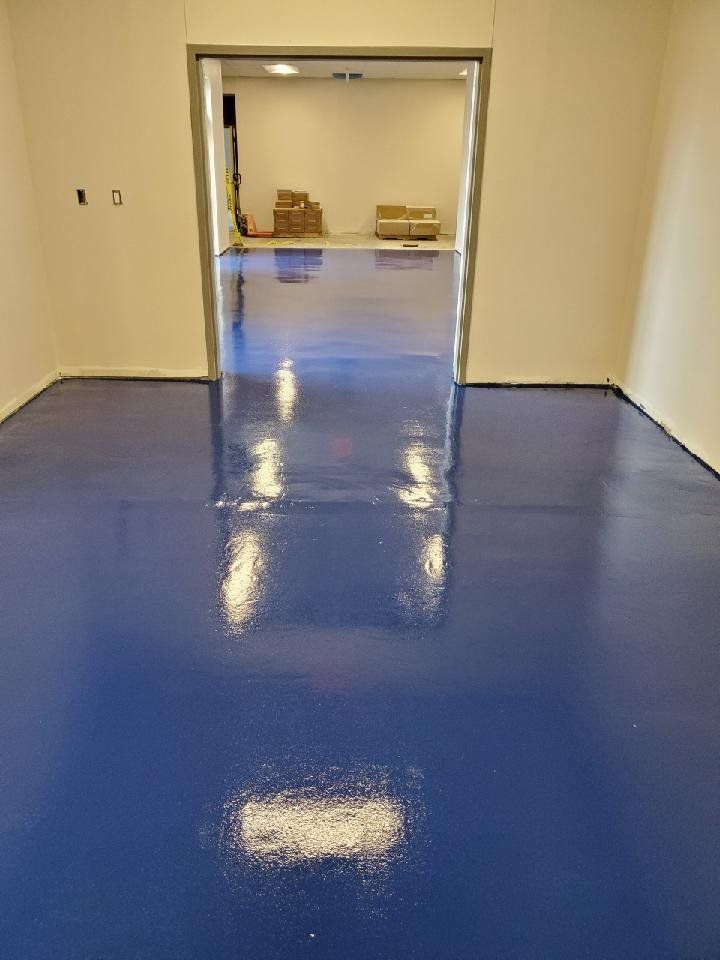 A blue floor in a room with a doorway leading to another room.