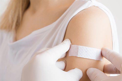 Putting Bandage On Woman's Shoulder — Memphis, TN — Vaccine Injury Lawyers Putting Bandage On Woman's Shoulder — Memphis, TN — Vaccine Injury Lawyers