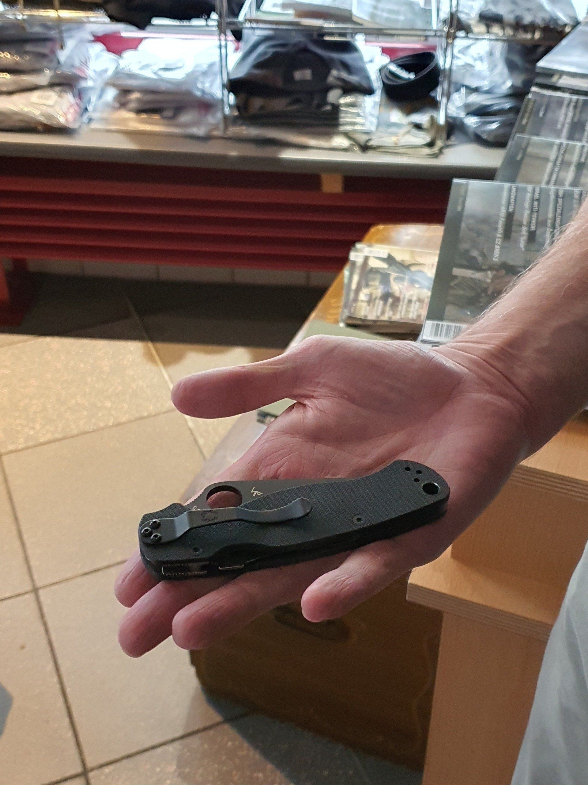 Eine Person, die ein geschlossenes schwarzes Klappmesser in der Hand hält.