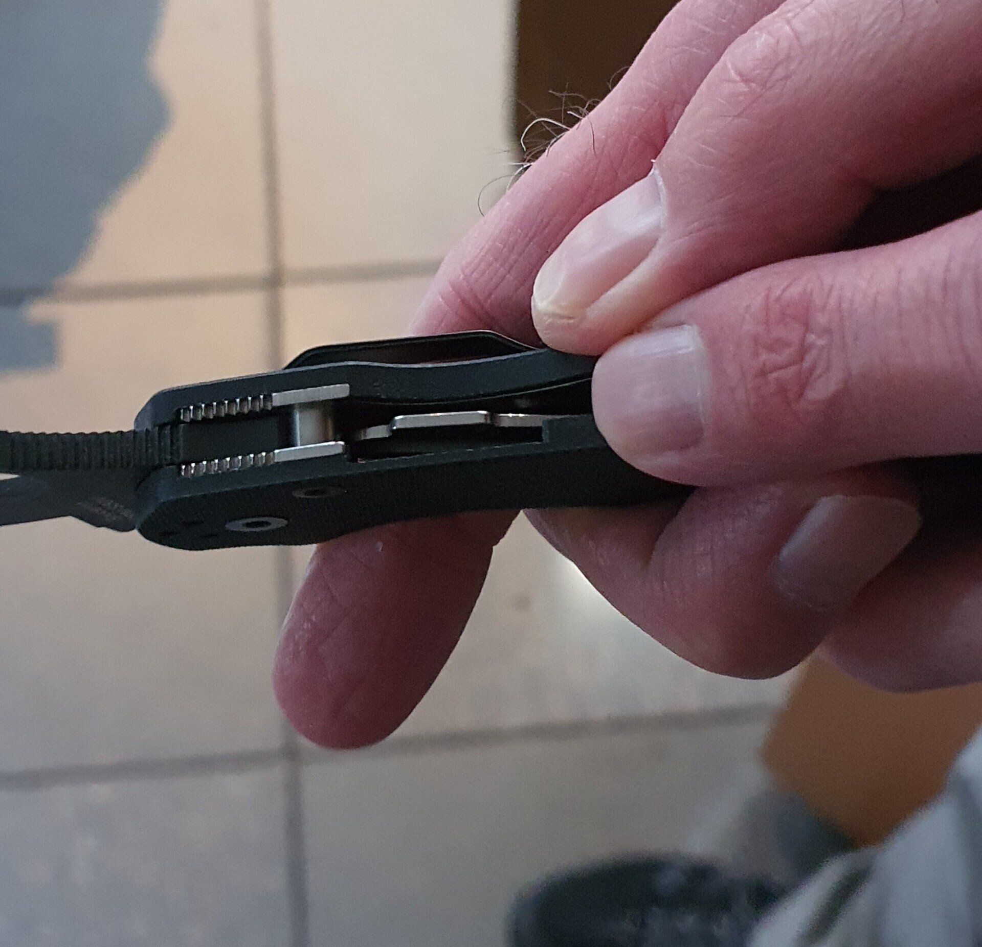 Die Hand einer Person öffnet ein schwarzes Klappmesser. Konzentrieren Sie sich auf die inneren Mechanismen und die Klinge.