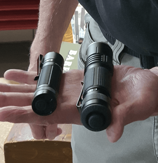 Eine Person hält zwei schwarze Taschenlampen unterschiedlicher Größe, Nahaufnahme.