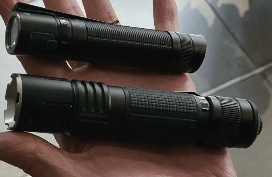Zwei schwarze Taschenlampen, eine kleinere oben, in einer Hand gehalten.