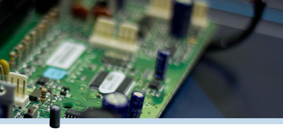 Gros plan sur une carte de circuit imprimé verte comportant divers composants électroniques, notamment des condensateurs et des puces.