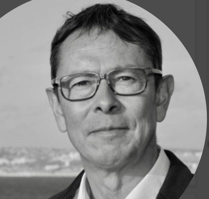 Une photo en noir et blanc d'un homme portant des lunettes et un costume