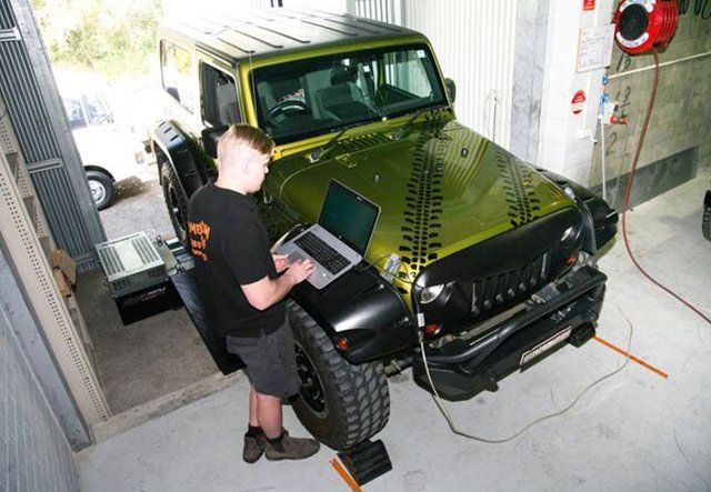 man working on green jeep