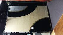 Black and beige abstract rug with curved corner cutouts on a floor under furniture.