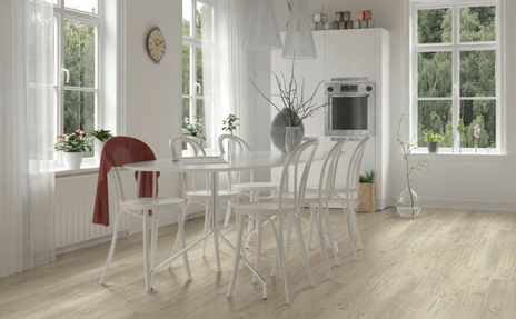 Bright white dining room with a glass table, chairs, large windows, and light wood floors