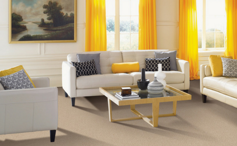 Bright living room with white sofas, yellow curtains, and a gold coffee table by a window.