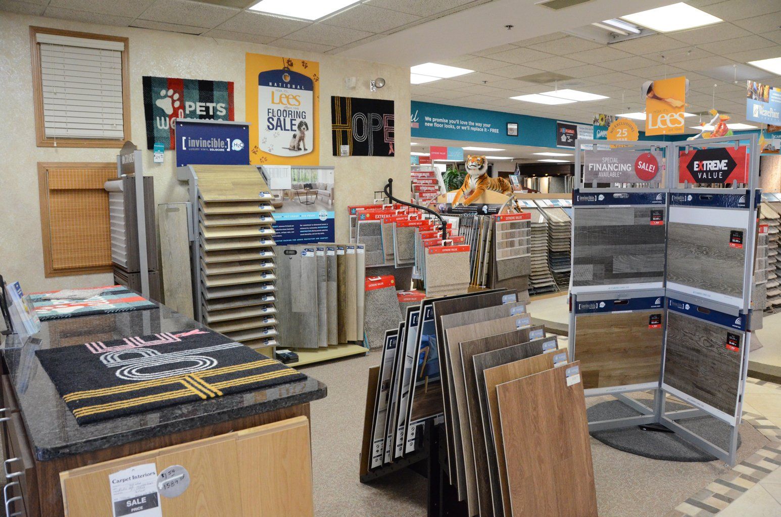 Store display area with metal racks, framed art, and signs in a bright retail shop.