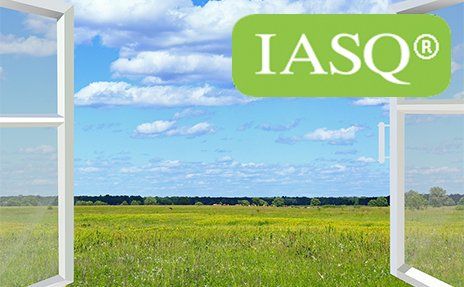 Open window over green field and blue sky with IASQ logo