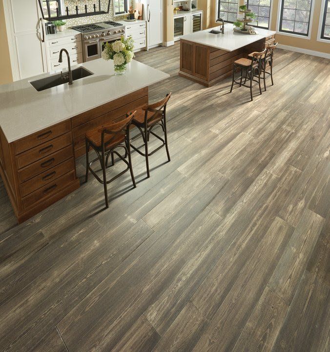 Bright modern kitchen with large island, wood cabinetry, bar stools, and wide plank flooring