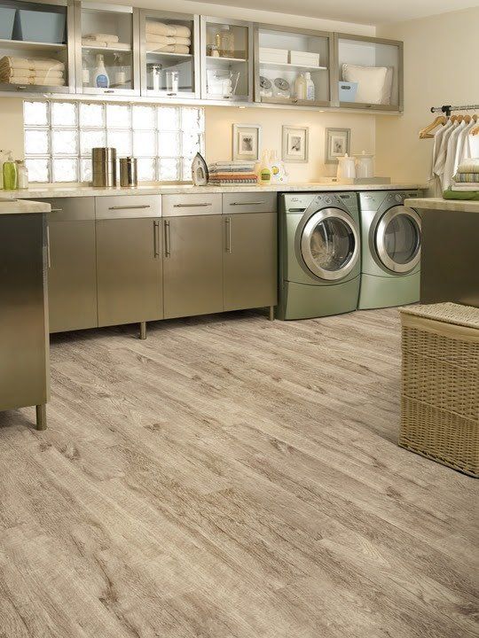Modern laundry room with stainless cabinets, front-load washer and dryer, and light wood flooring