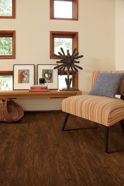 Cozy living room with striped chair, brown floor, small windows, framed art, and decorative sculpture
